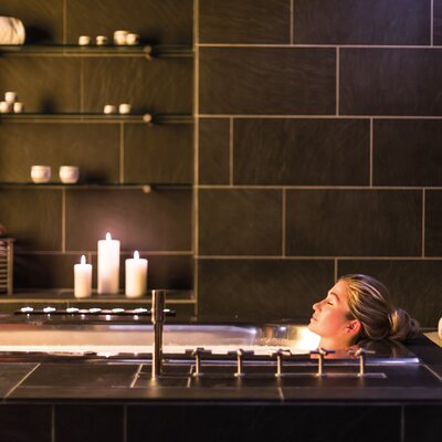 Frau entspannt bei Kerzenschein in einer Badewanne im Badehaus Norderney