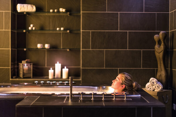 Frau entspannt bei Kerzenschein in einer Badewanne im Badehaus Norderney