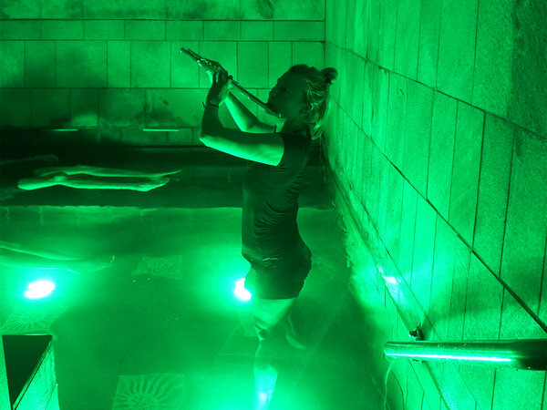 Eine Frau spielt Querflöte in einem Schwimmbecken.
