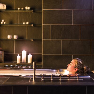 Frau entspannt bei Kerzenschein in einer Badewanne im Badehaus Norderney