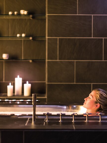 Frau entspannt bei Kerzenschein in einer Badewanne im Badehaus Norderney
